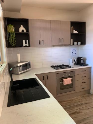 a kitchen with a stove and a counter top at Shepparton Lakeside Serviced Apartment in Shepparton