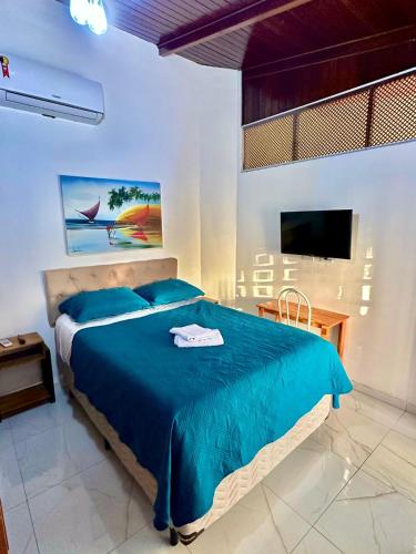 a bedroom with a blue bed and a television at Home Beach Mar Conforto Self-Hosted in Aquiraz