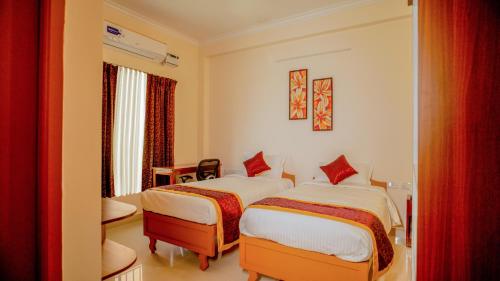 um quarto de hotel com duas camas e uma cadeira em Revostay Royel by Crossway em Chennai