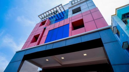 a pink and blue building with the sky in the background at Revostay Royel by Crossway in Chennai