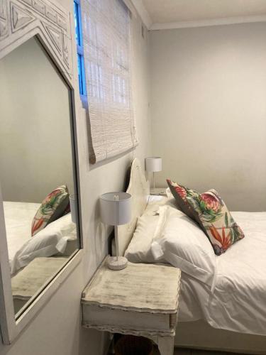 een slaapkamer met een bed, een spiegel en een tafel bij Blue Cottage on Berea in Durban