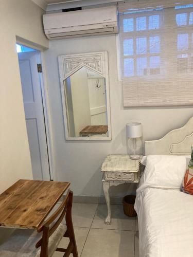 een slaapkamer met een bed, een tafel en een spiegel bij Blue Cottage on Berea in Durban