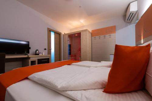 a bedroom with a large bed with an orange pillow at Albergo Casavecchia in Tiarno di Sopra