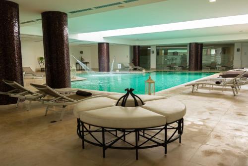 a large swimming pool with a round chair in a building at Grand Hotel Villa Itria Congress & Spa in Viagrande