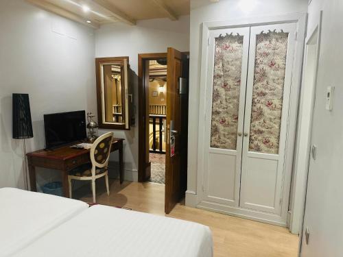 a bedroom with a bed and a desk and a door at Sacristia de Santa Ana in Seville