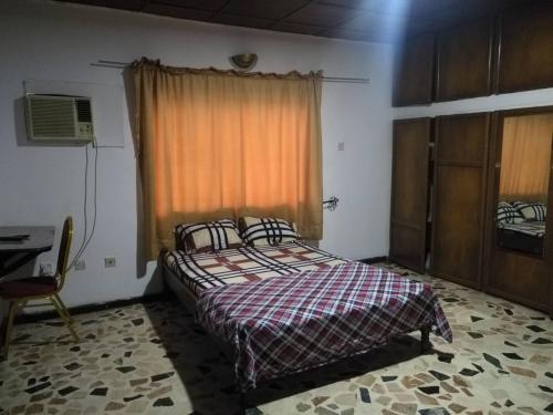 a bedroom with a bed and a desk and a window at Unrivaled comfort at Vals Residence with king-sized bed in Lagos