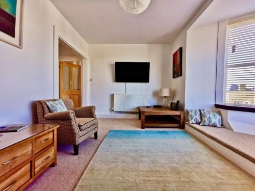 a living room with a couch and a tv at Seashells at 2 TRENCROM COURT ST IVES in Carbis Bay
