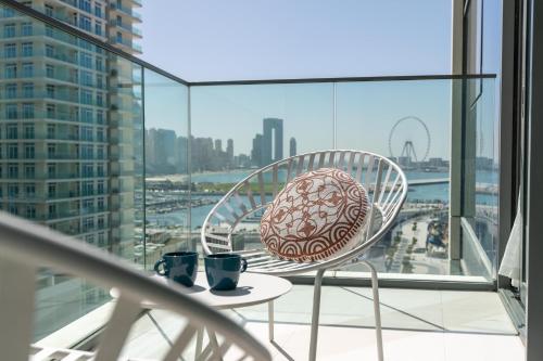 a chair and two cups on a table on a balcony at Vacay Lettings - Private Beach Access -Emaar Beachfront in Dubai