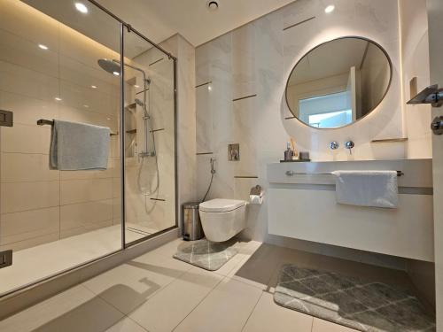 a bathroom with a shower and a toilet and a mirror at Vacay Lettings - Private Beach Access -Emaar Beachfront in Dubai