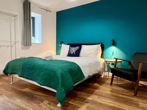 Un dormitorio con una cama verde y blanca y una silla en City SuperHost NQ & City Centre 1 BR with Parking, en Mánchester
