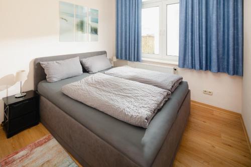 1 cama en un dormitorio con cortinas azules en Villa Marie Wohnung 1, Norderney en Norderney