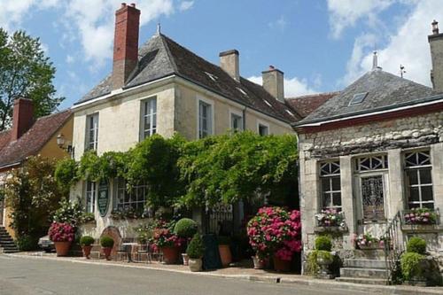 an old house with flowers and plants on a street at Location au mois - Perspective Perche - La Perrière in La Perrière