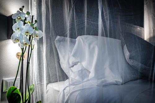uma cama branca com uma cortina e um vaso de flores em Mama's Home Florence em Florença