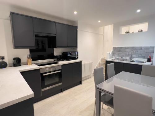 a kitchen with black cabinets and a table with chairs at The Dragon Pad Boutique Apartment in Royal Tunbridge Wells