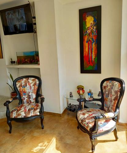 two chairs in a room with a table and a painting at Hotel San Lorenzo in Bucaramanga