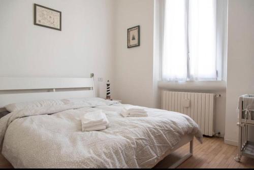 um quarto branco com uma cama com duas toalhas em ALTIDO Classic flat near Basilica di Sant'Ambrogio em Milão