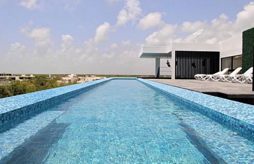 ein großer Pool mit Stühlen und ein Gebäude in der Unterkunft Beautiful 1 Bedroom Aldea Zama En Tulum in Tulum