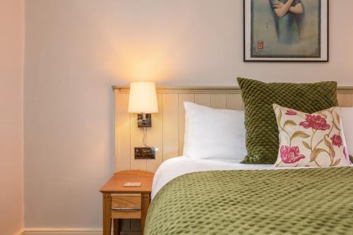 a bedroom with a bed with a green blanket and pillows at The Black Swan Inn in Pickering