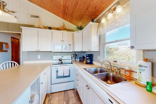 a kitchen with white cabinets and a sink and a window at Sea Escape 25 in Avon