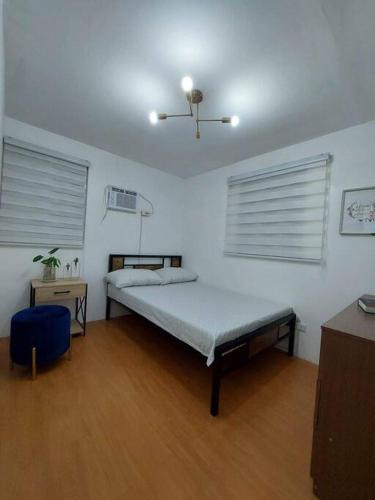 a bedroom with a bed and two windows at Cosy House in Bacolod City in Bacolod