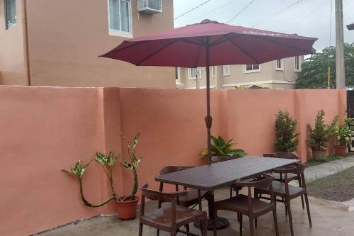 a picnic table with an umbrella and some chairs at Cosy House in Bacolod City in Bacolod