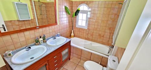 a bathroom with two sinks and a tub and a toilet at Ferienhaus CALETA SUEÑO in La Guirra