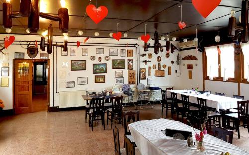 un restaurante con mesas, sillas y corazones en la pared en Tassi Halászcsárda-Harcsa ház, en Tass