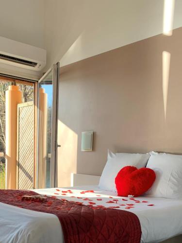 a red heart pillow sitting on top of a bed at Hôtel L'ile Du Saussay in Itteville