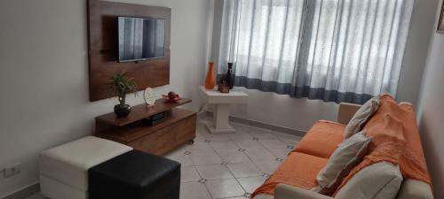 ein Wohnzimmer mit einem Sofa und einem Tisch in der Unterkunft Apto 1 suíte a 30 mts. da Praia do Tombo - Guarujá in Guarujá
