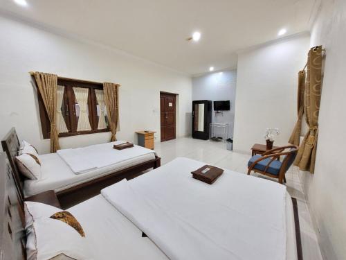a room with two beds and a chair in it at Ndalem Katong Guest House Ponorogo in Ponorogo