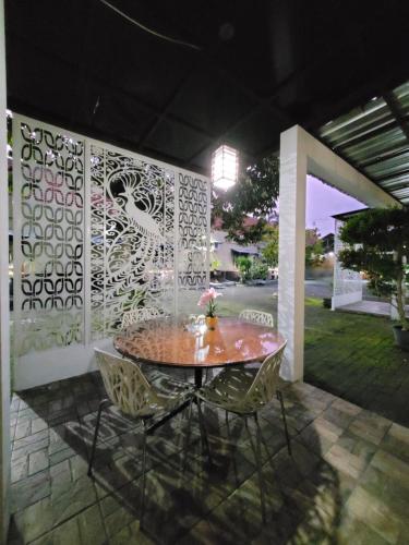 a table and chairs on a patio at night at Ndalem Katong Guest House Ponorogo in Ponorogo