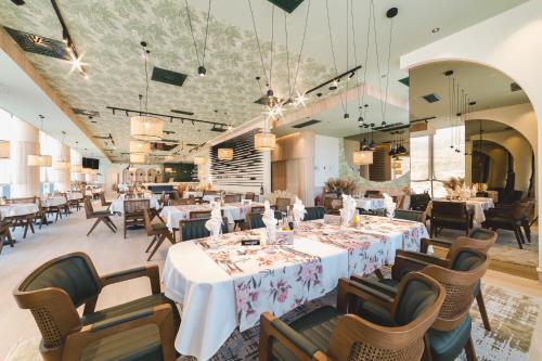 Hotel Aurel Coast في كوتور: غرفة طعام مع طاولات بيضاء وكراسي وحارق طاولات