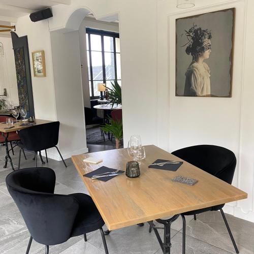 a dining room with a wooden table and black chairs at Le Clos Du Pontic Logis et Cit'Hotel in Landerneau