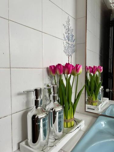 a bathroom sink with pink tulips in vases on a shelf at lily maison in Tanah Rata
