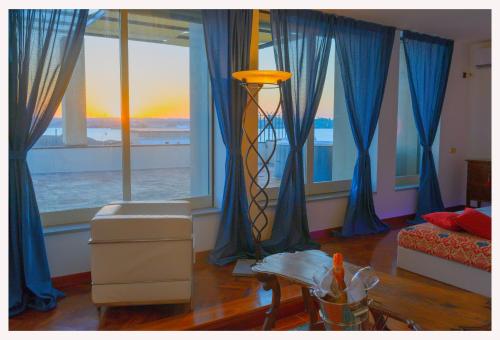 un soggiorno con tende blu e una camera con tavolo di Villa Sul Molo tra Siracusa e Catania ad Augusta