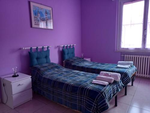 two beds in a room with purple walls at Affittacamere Appartamento colorato in Ferrara