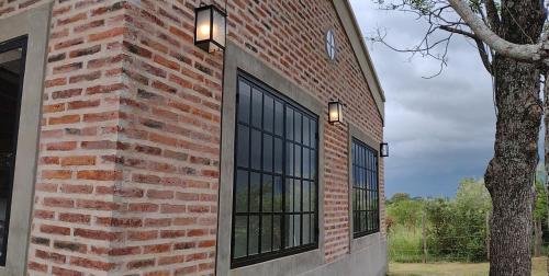 una pared de ladrillo con dos ventanas y un árbol en JPE en Mercedes