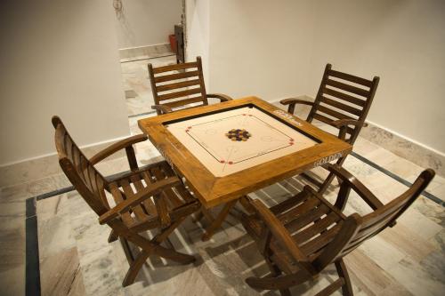 a wooden table with chairs and a clock on it at The Fern Bambora Fort, Bambora, Udaipur in Udaipur
