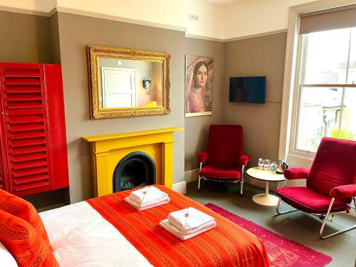 a bedroom with a bed and two chairs and a fireplace at Snooze in Brighton & Hove
