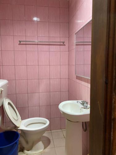 Baño de color rosa con aseo y lavamanos en Muna’s Homestay en Kota Belud