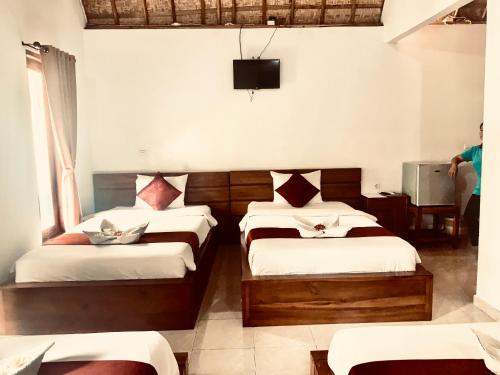 a bedroom with two beds and a tv on the wall at Jona Bungalow in Nusa Penida
