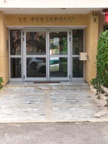une porte d'entrée d'un bâtiment avec un panneau sur celui-ci dans l'établissement Résidence Le Persepolis 50 m de la mer, à Cagnes-sur-Mer