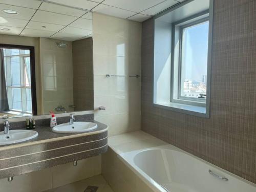 ein Badezimmer mit zwei Waschbecken, einer Badewanne und einem Fenster in der Unterkunft Luxery home with stunning sea view in Ajman 