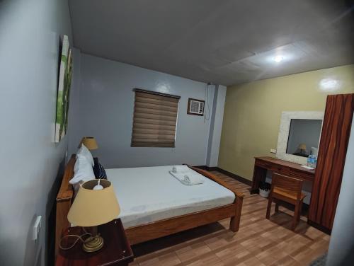 a small bedroom with a bed and a desk at Calicoan Villa in Sarog