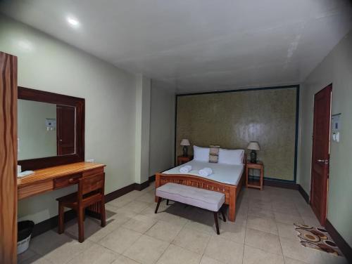 a bedroom with a bed and a desk and a mirror at Calicoan Villa in Sarog