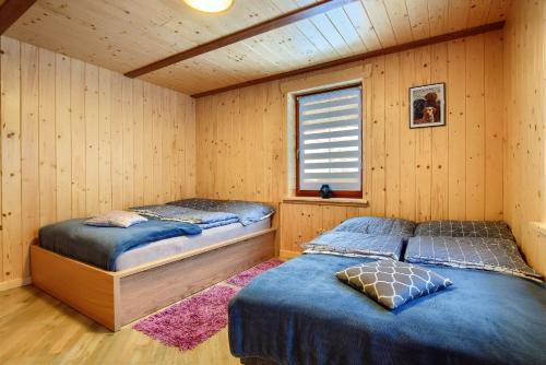two beds in a room with wooden walls at DOM ZORA in Brenna