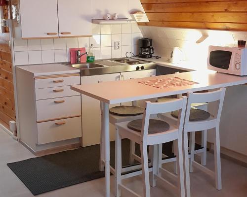 a small kitchen with a table and two stools at Karemajat Cottage Resort in Ylitornio