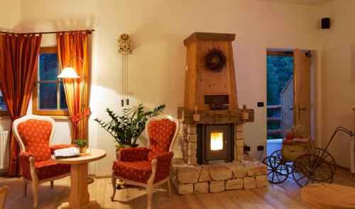a living room with a fireplace and chairs and a table at Villa Ortensia in San Vigilio Di Marebbe