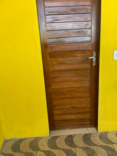 una puerta de madera en una habitación con una pared amarilla en Suítes Gold Star Village, en Majorlândia