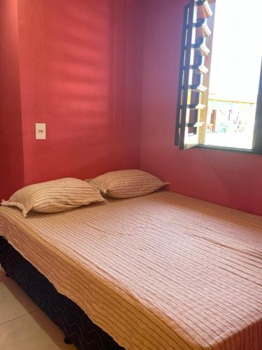 Cama en habitación con pared roja en Suítes Gold Star Village, en Majorlândia